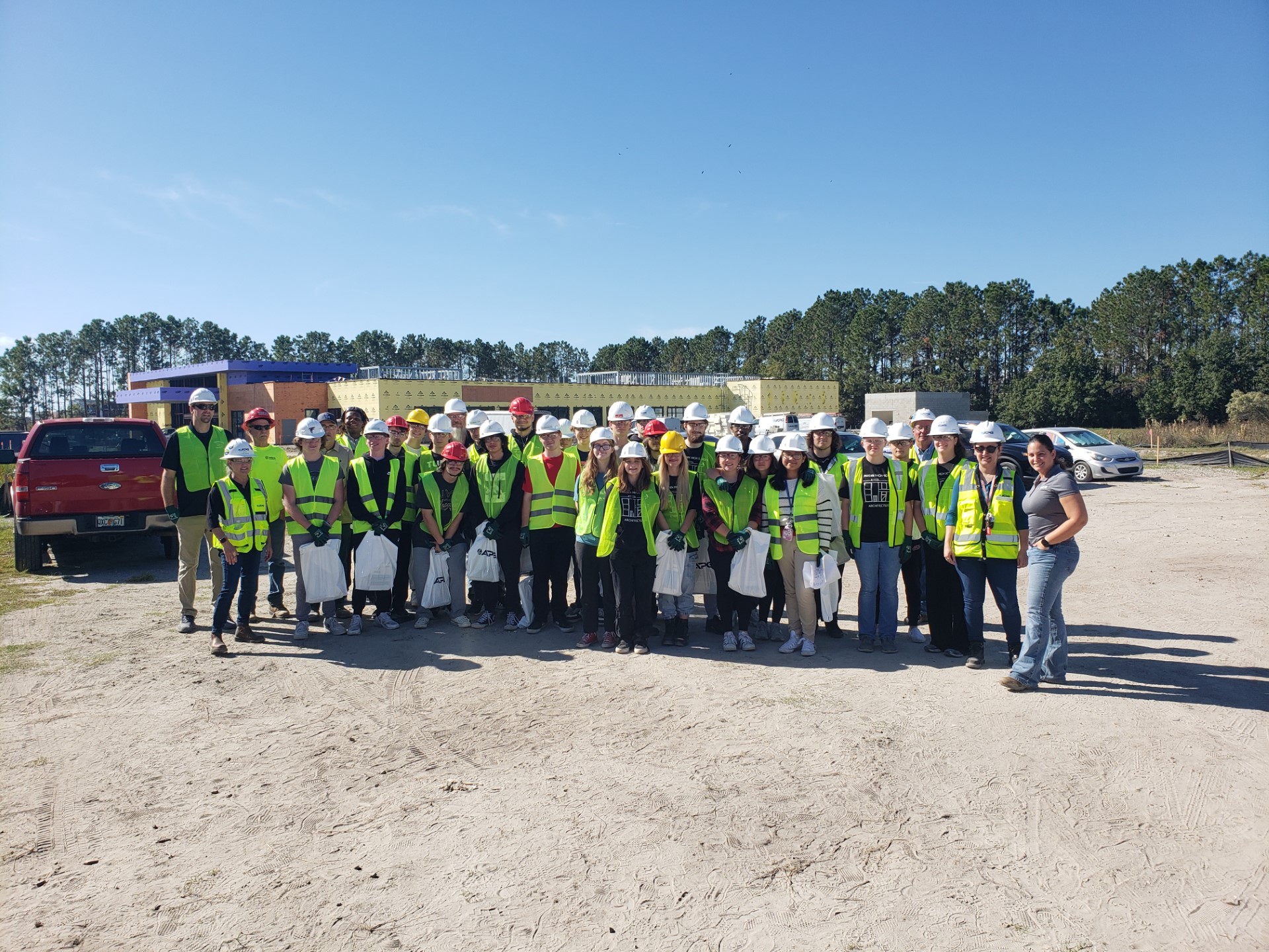 A group of people in safety vests and white helmetsDescription automatically generated